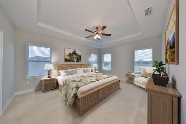 bedroom with a tray ceiling, visible vents, light carpet, and baseboards