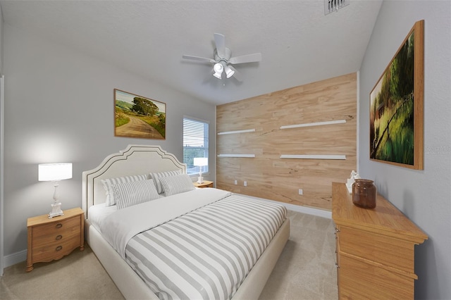 bedroom featuring light carpet, wood walls, ceiling fan, and visible vents