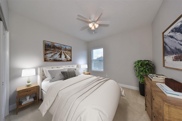 bedroom with ceiling fan, baseboards, and light colored carpet