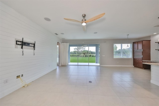 interior space with light tile patterned floors, ceiling fan, and baseboards