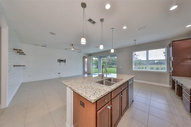 kitchen featuring visible vents, hanging light fixtures, a sink, and a center island with sink