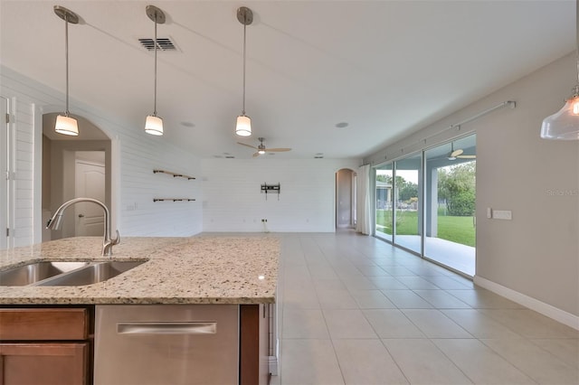 kitchen with arched walkways, visible vents, open floor plan, a sink, and light stone countertops