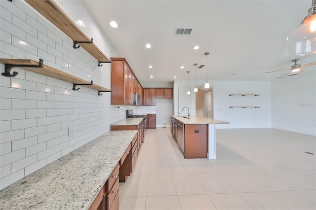 kitchen with decorative light fixtures, light stone countertops, stainless steel appliances, open shelves, and a sink