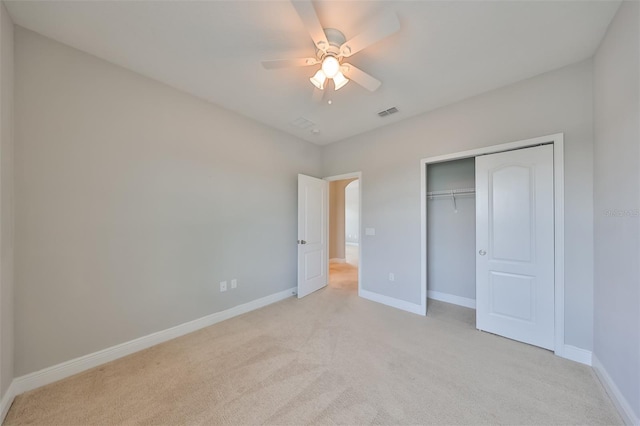 unfurnished bedroom with light carpet, ceiling fan, a closet, and baseboards