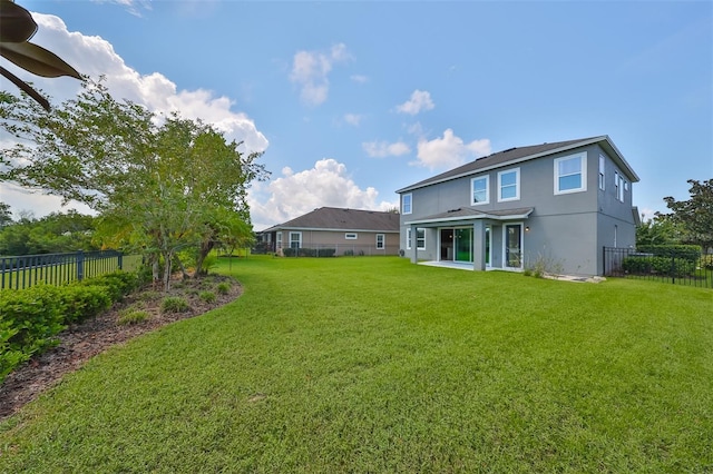 back of house featuring a fenced backyard, a yard, and stucco siding