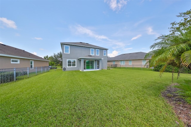 back of house with a lawn, a fenced backyard, and stucco siding