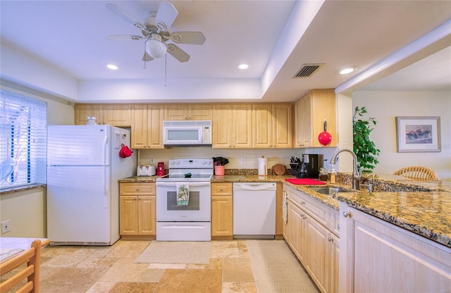 kitchen featuring light stone counters, visible vents, light brown cabinetry, a sink, and white appliances