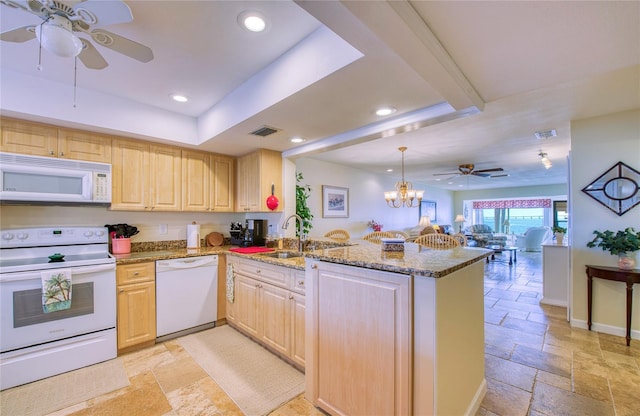 kitchen featuring a peninsula, white appliances, stone tile floors, and open floor plan