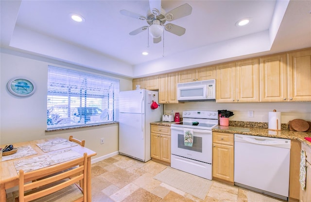 kitchen with white appliances, a tray ceiling, light stone counters, and recessed lighting