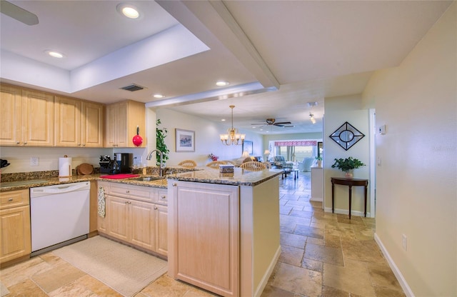 kitchen with a peninsula, stone tile floors, dishwasher, and light brown cabinetry