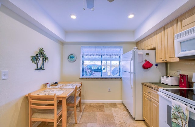 kitchen featuring white appliances, stone tile floors, baseboards, and light brown cabinetry