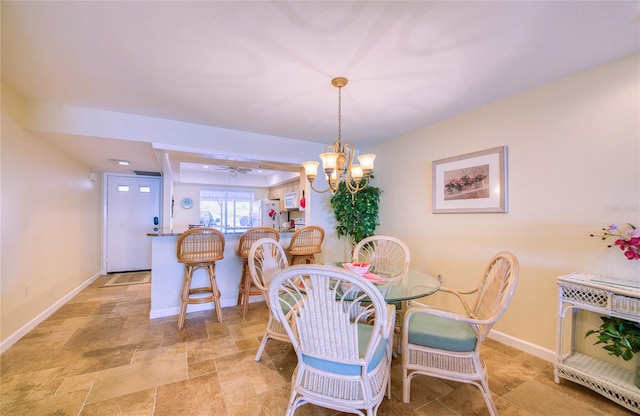 dining area featuring a chandelier, stone finish floor, and baseboards