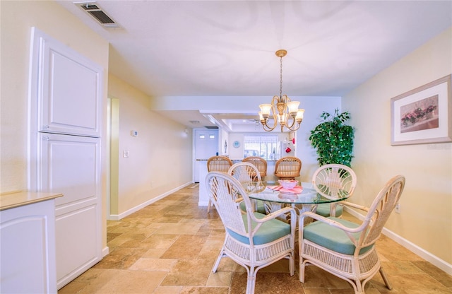 dining space featuring stone finish floor, an inviting chandelier, baseboards, and visible vents