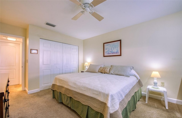 bedroom featuring baseboards, visible vents, light colored carpet, ceiling fan, and a closet