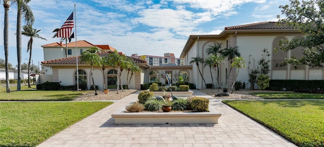 back of property featuring a tile roof, a yard, and stucco siding