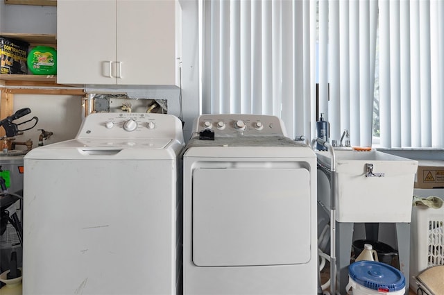 clothes washing area with cabinet space, independent washer and dryer, and a sink