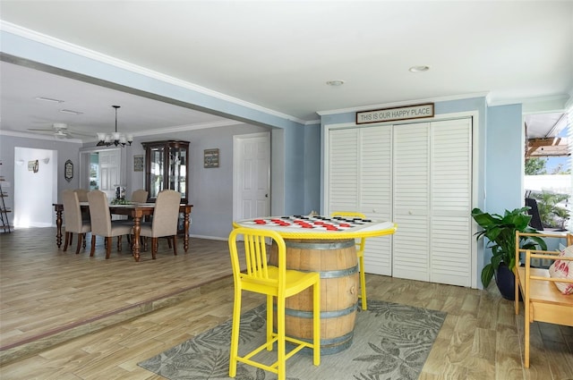 playroom with light wood finished floors, baseboards, ornamental molding, and an inviting chandelier