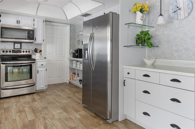 kitchen with visible vents, appliances with stainless steel finishes, hanging light fixtures, light countertops, and white cabinetry