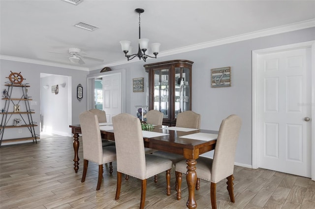 dining room with visible vents, light wood-style floors, ornamental molding, baseboards, and ceiling fan with notable chandelier