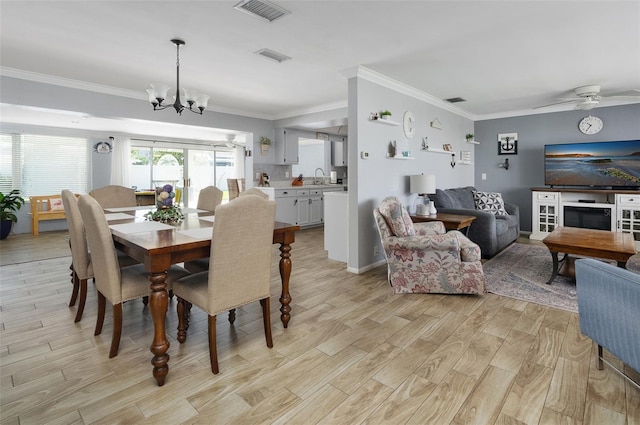 dining space with ceiling fan with notable chandelier, ornamental molding, light wood-type flooring, and visible vents