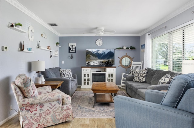 living area with ornamental molding, visible vents, ceiling fan, and light wood finished floors