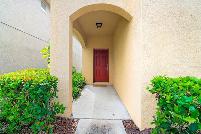 view of exterior entry with visible vents and stucco siding