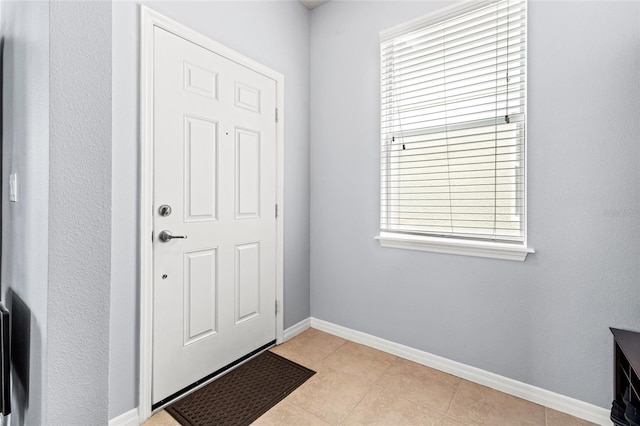 doorway with baseboards and light tile patterned floors