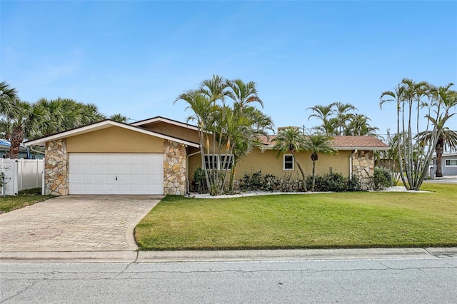 ranch-style house with a front lawn, driveway, an attached garage, fence, and stucco siding