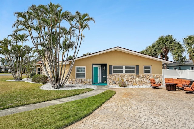 view of front of property featuring stone siding, a front yard, stucco siding, and fence