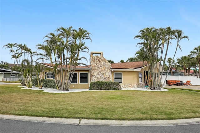 single story home featuring a front lawn, a chimney, stucco siding, and fence