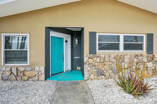 doorway to property featuring stone siding and stucco siding