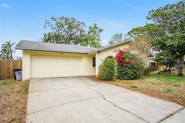 ranch-style home with an attached garage, fence, concrete driveway, and stucco siding