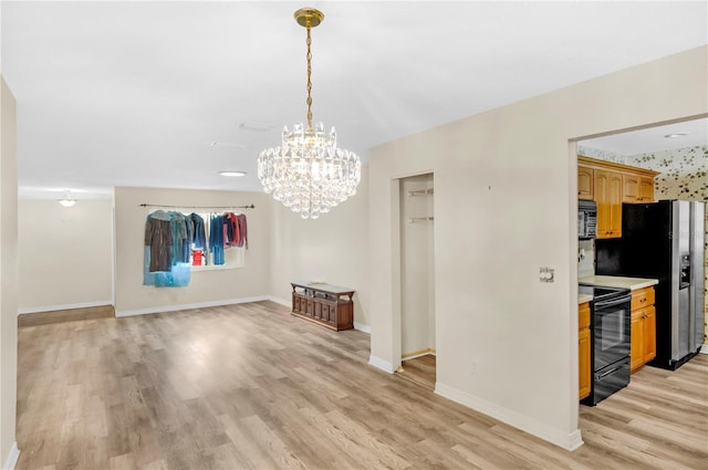 unfurnished dining area with an inviting chandelier, light wood-style flooring, and baseboards