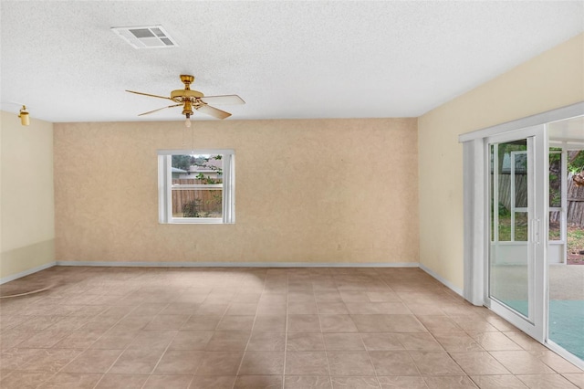 unfurnished room featuring a ceiling fan, a textured ceiling, visible vents, and a wealth of natural light