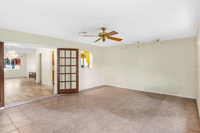 spare room with ceiling fan with notable chandelier, a textured ceiling, visible vents, and baseboards