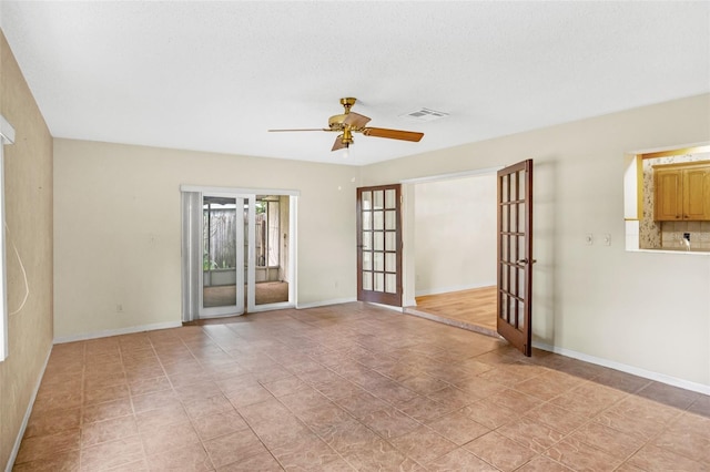 unfurnished room with baseboards, french doors, visible vents, and a ceiling fan