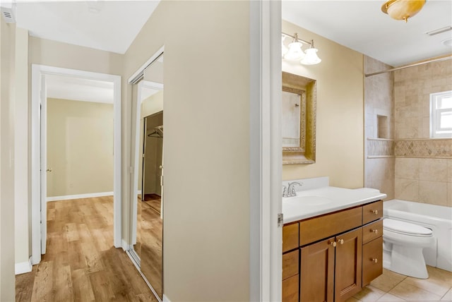 bathroom with bathtub / shower combination, toilet, visible vents, vanity, and baseboards