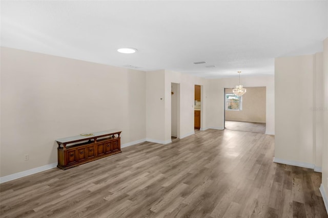 unfurnished room featuring light wood-style flooring, baseboards, and a chandelier