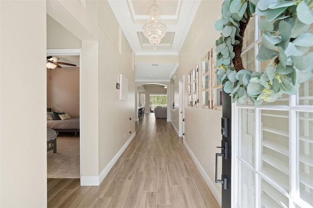 corridor with arched walkways, light wood-style floors, crown molding, baseboards, and a chandelier