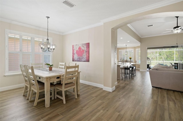 dining room with visible vents, crown molding, baseboards, wood finished floors, and arched walkways