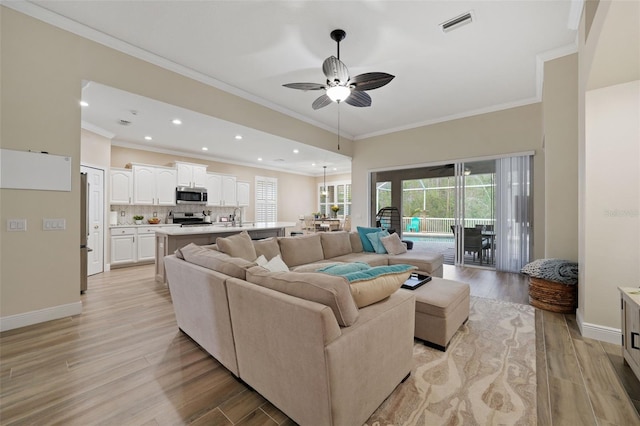 living area with crown molding, baseboards, and light wood finished floors