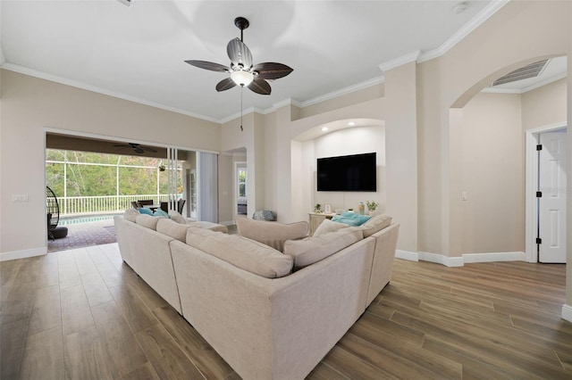 living room featuring visible vents, crown molding, baseboards, a sunroom, and wood finished floors