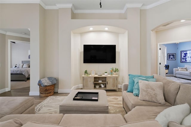 living room with wood finished floors, recessed lighting, arched walkways, crown molding, and baseboards