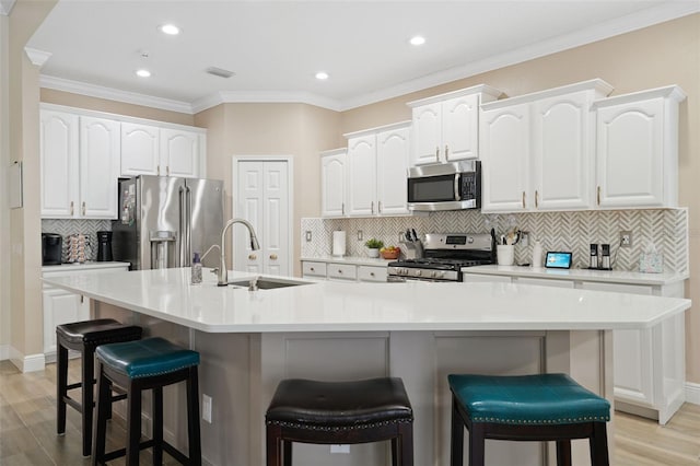 kitchen featuring a kitchen breakfast bar, white cabinets, appliances with stainless steel finishes, and a sink