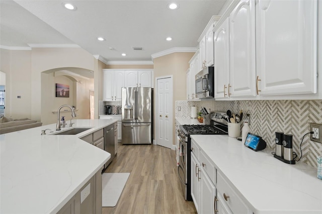 kitchen featuring a sink, stainless steel appliances, ornamental molding, and light wood-style flooring