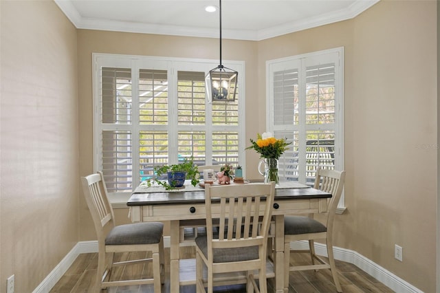 dining space with baseboards, wood finished floors, and ornamental molding