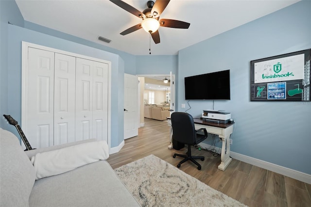 home office featuring visible vents, a ceiling fan, baseboards, and wood finished floors