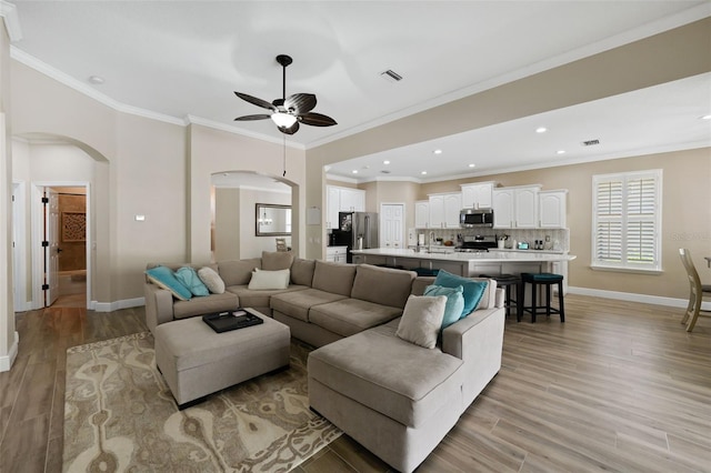 living area with baseboards, arched walkways, and light wood-type flooring