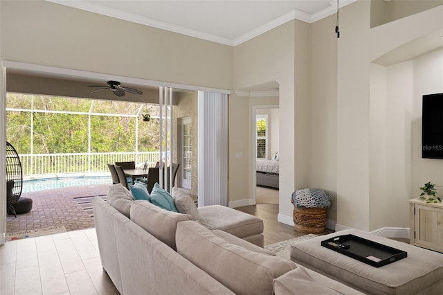 living room with crown molding, light wood-type flooring, baseboards, and ceiling fan