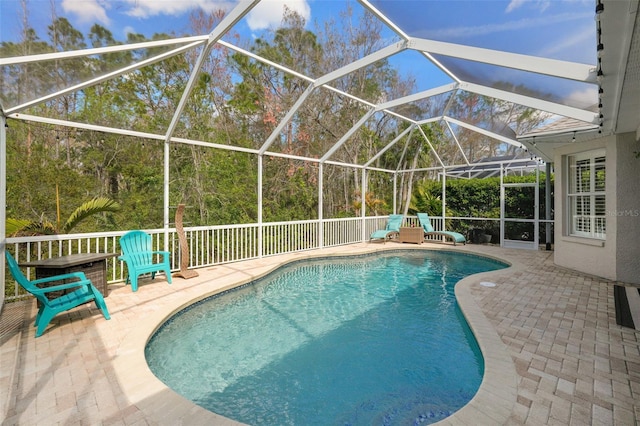 outdoor pool with glass enclosure and a patio